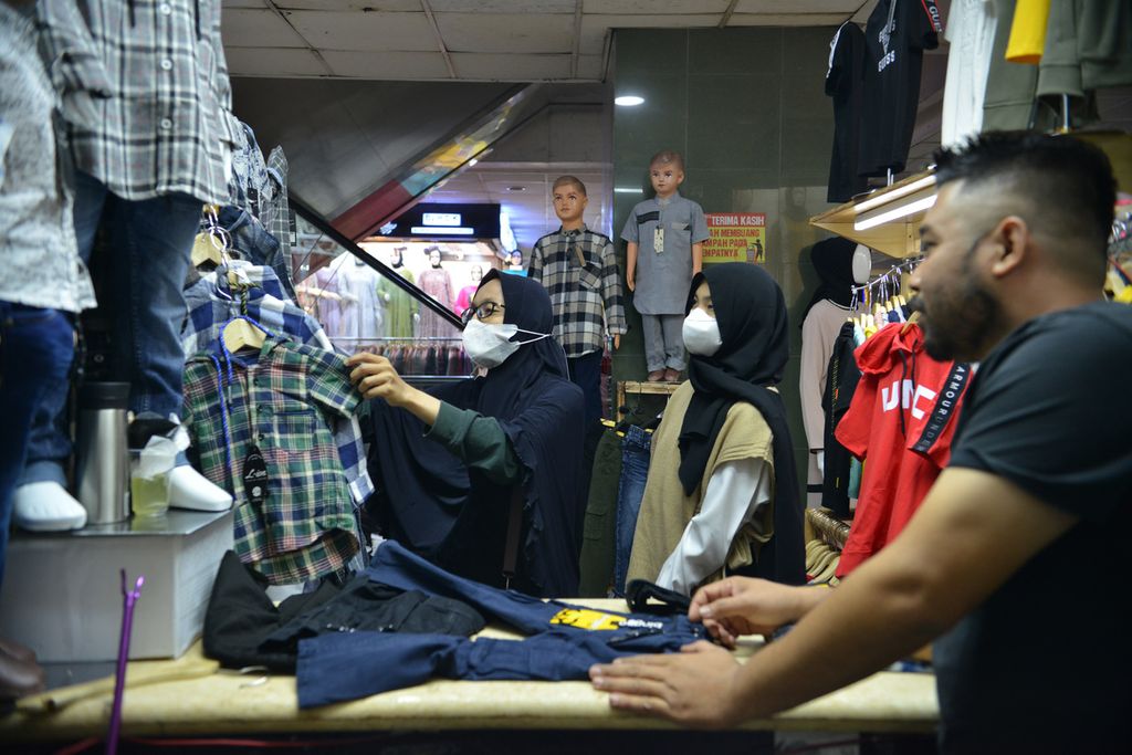 Sejumlah warga memilih pakaian yang dijual di salah satu toko di Pasar Tanah Abang, Jakarta Pusat, Senin (2/1/2022). 