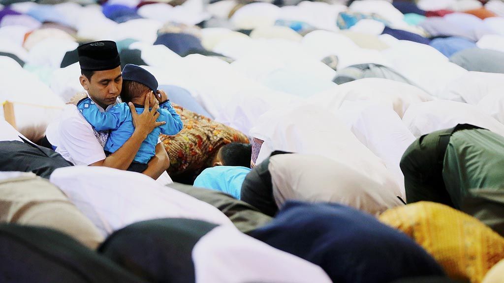 Dengan menggendong anaknya, seorang warga tetap khusyuk menjalankan sholat Idul Fitri 1438 H di MAsjid Istiqlal, Jakarta, Minggu (25/6).