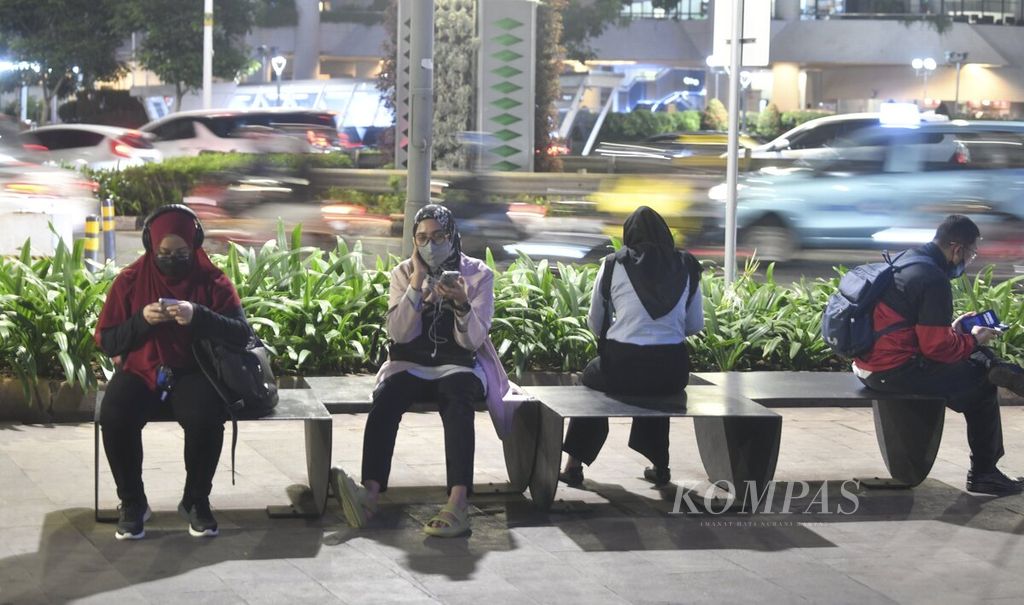 Sejumlah pekerja beristirahat sambil duduk di bangku yang berada di jalur pedestrian Jalan Sudirman, Jakarta, saat pulang kantor, Kamis (17/11/2022) malam. 