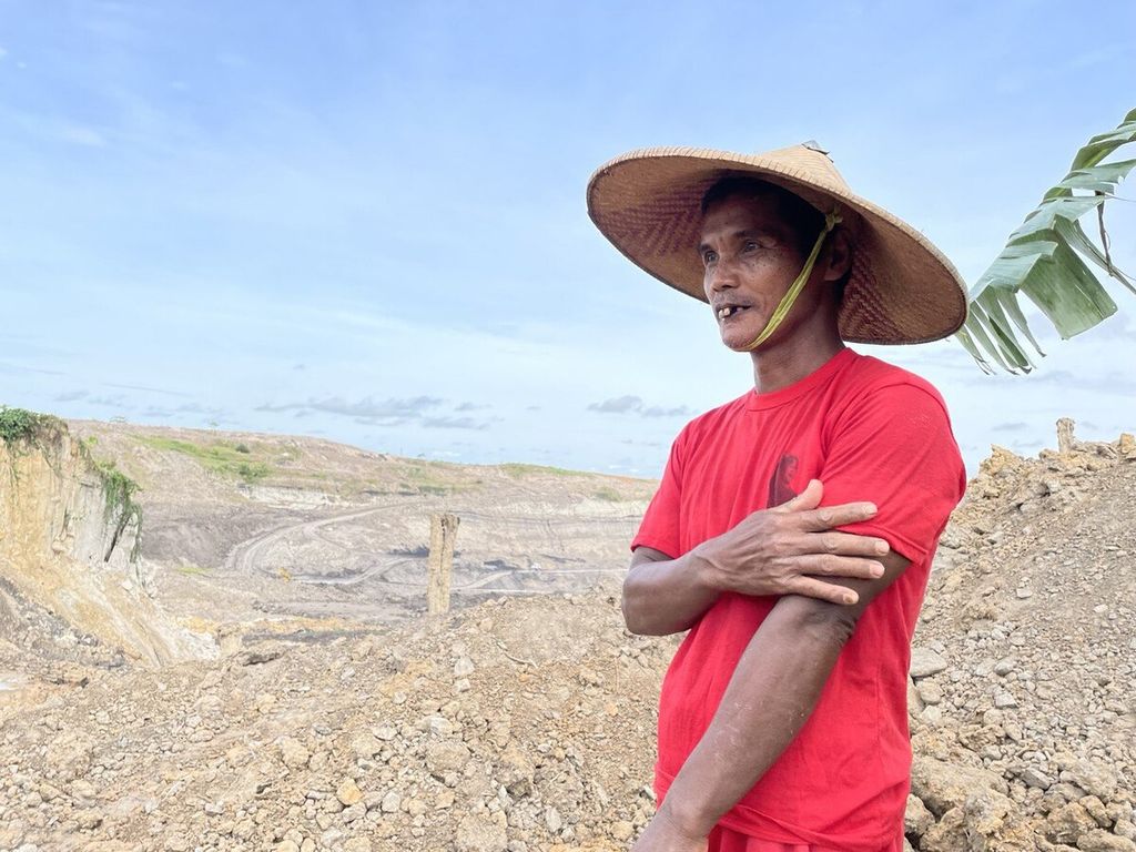 Syadari (45) berdiri di persawahan yang berhadapan langsung dengan tambang batubara di Desa Desa Karang Tunggal, Kecamatan Tenggarong Seberang, Kabupaten Kutai Kartanegara, Kalimantan Timur, Sabtu (7/1/2023).
