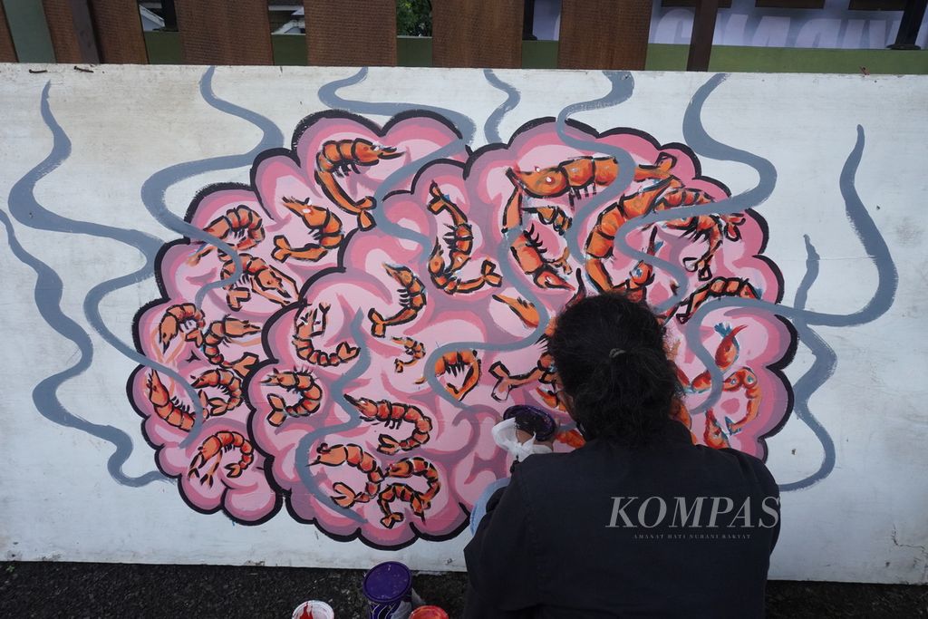 Seniman melukis gambar otak dan udang di halaman Pengadilan Negeri Jepara, Jawa Tengah, Kamis (4/4/2024). 