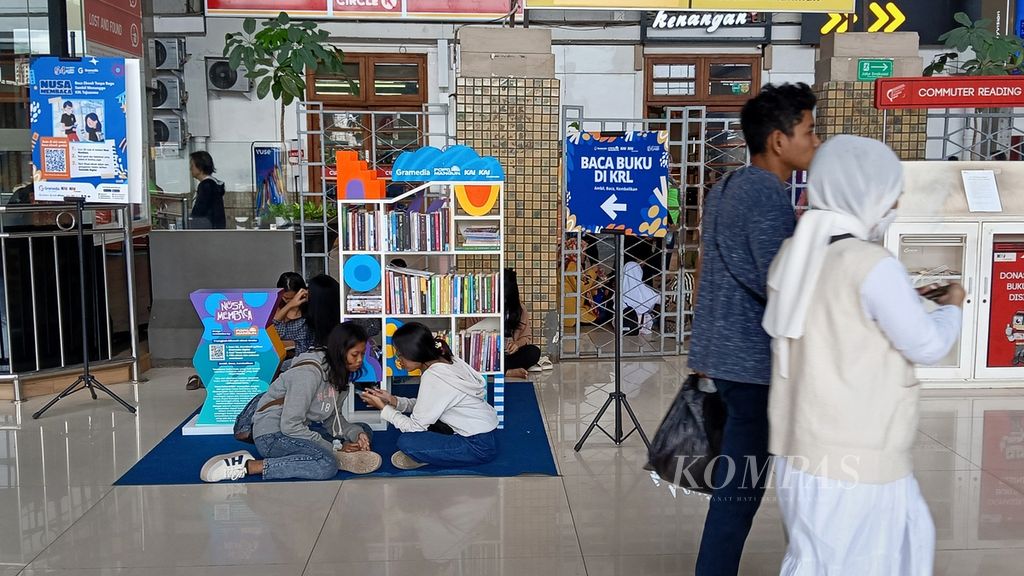 Suasana perpustakaan mini Gramedia di Stasiun Jakarta Kota, Sabtu (2/3/2024). Dua anak membuka gawai usai memindai kode batang <i>e-book</i>.