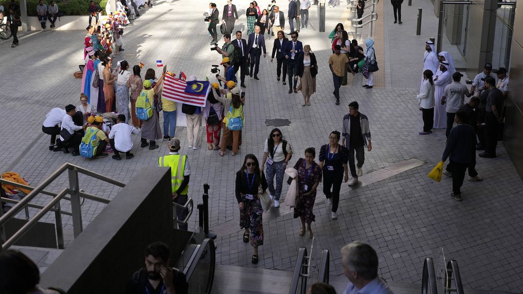 Sejumlah delegasi berjalan melewati kelompok orang yang berunjuk rasa di tempat penyelenggaraan COP28, Pertemuan Puncak Iklim yang digelar PBB di Dubai, Uni Emirat Arab, Kamis (30/11/2023). 