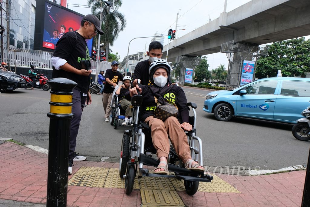 Pengguna kursi roda dibantu pendampingnya untuk mengakses trotoar di kawasan Jakarta Selatan, Rabu (1/3/2023). Kala itu ada belasan penyandang disabilitas yang antara lain terdiri dari pengguna kursi roda, tunanetra, dan orang tuli menyusuri Jakarta dari Stasiun MRT Dukuh Atas ke Stasiun MRT ASEAN untuk memperingati Hari Kursi Roda Internasional 2023.