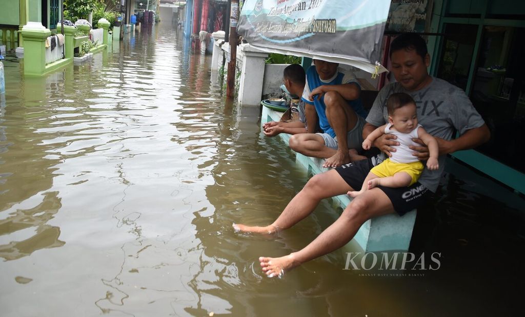 Ilustrasi. Warga di depan rumahnya saat banjir di Gang Tanjung, Kecamatan Gempol, Kabupaten Pasuruan, Jawa Timur, Senin (2/11/2020). 