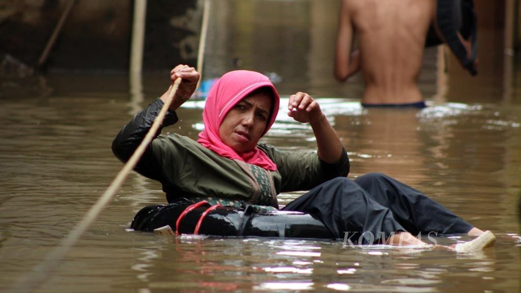 Warga menggunakan ban bekas saat melintasi banjir di Kelurahan Andir, Baleendah, Kabupaten Bandung, Jawa Barat, Sabtu (6/4/2019). Lebih dari 700 orang mengungsi akibat banjir luapan Sungai Citarum tersebut.