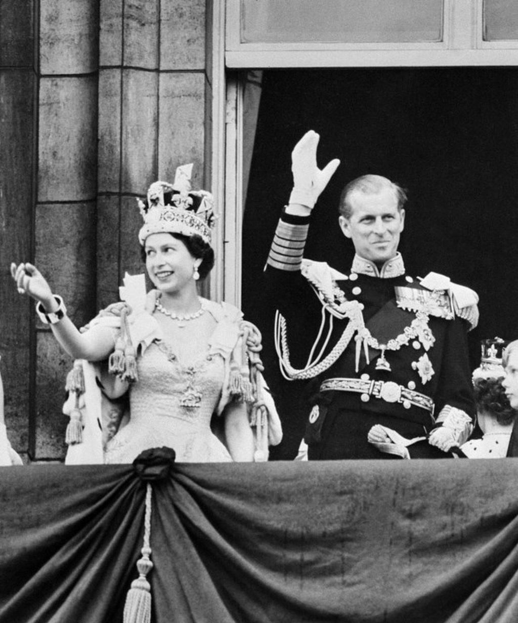 Ratu Elizabeth II dari Inggris Raya (kiri) didampingi suaminya, Pangeran Philip, Duke of Edinburgh melambai tangan ke kerumunan warga pada 2 Juni 1953 di London setelah dinobatkan di Gereja Westminter Abbey. Tampak Ratu mengenakan Imperial State Crown saat hendak meninggalkan tempat upacara penobatan.