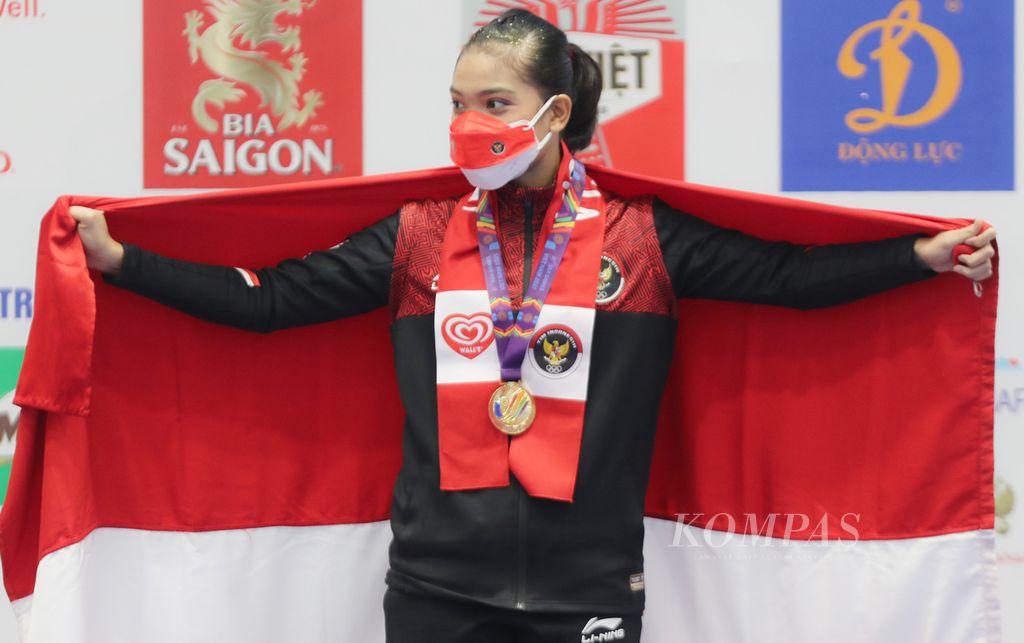 Atlet wushu Indonesia, Alisya Mellynar, mengibarkan bendera Merah Putih seusai meraih medali emas cabang Wushu pada SEA Games Vietnam 2021 di Cau Giay Gymnasium, Hanoi, Vietnam, Sabtu (14/5/2022). Alisya merupakan debutan di SEA Games.