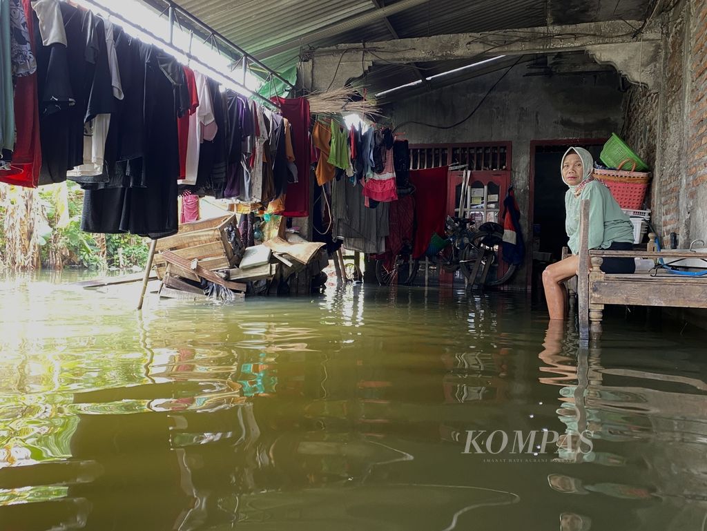 Sopiyah (59), warga Desa Sayung, Kecamatan Sayung, Kabupaten Demak, Jawa Tengah, duduk di teras rumahnya, Rabu (10/4/2024). Sopiyah bersedih karena pada Lebaran kali ini, rumahnya sepi lantaran anak-anak dan adiknya tak bisa berkunjung karena banjir. 