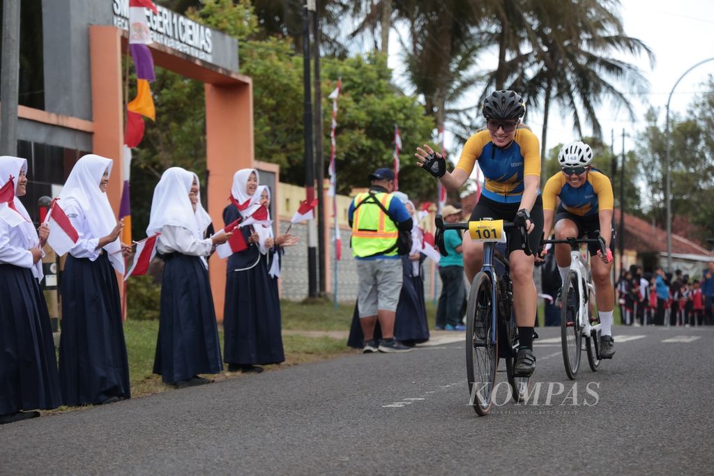 Para pebalap menyapa siswa SMPN 1 Ciemas saat melintasi kawasan Tamanjaya, Sukabumi, Jawa Barat, pada etape ke-1 Cycling de Jabar 2023, Sabtu (8/7/2023). 