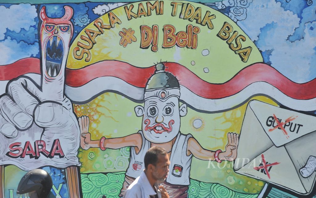 Warga melintas di depan mural bertema Pilkada Serentak di Jalan Raya Ahmad Yani, Kecamatan Waru, Sidoarjo, Jawa Timur, Senin (24/8/2020). Mural mengajak masyarakat untuk aktif berpartisipasi dan menolak segala bentuk politik uang dan hoaks pada Pilkada yang akan diselenggarakan pada 9 Desember 2020. Mural bergambar kartun digunakan oleh KPU sebagai sarana kampanye yang menarik. 