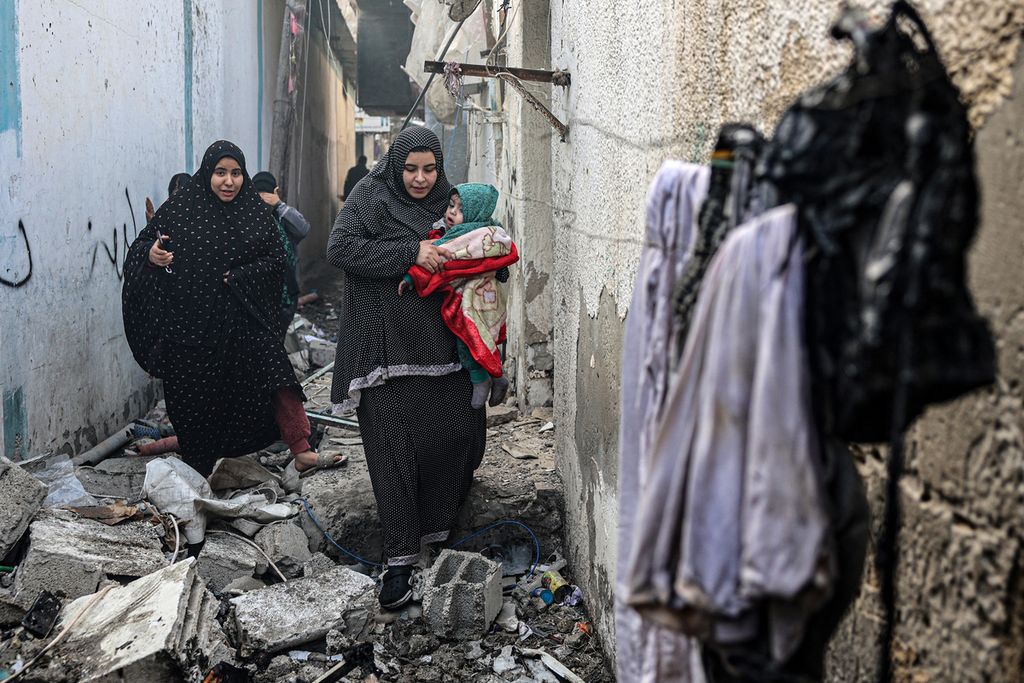 Warga menyusuri gang yang dipenuhi puing-puing setelah pengeboman Israel semalaman di Rafah di Jalur Gaza selatan di tengah berlanjutnya pertempuran antara Israel dan kelompok militan Palestina, Hamas, Minggu (25/2/2024). 