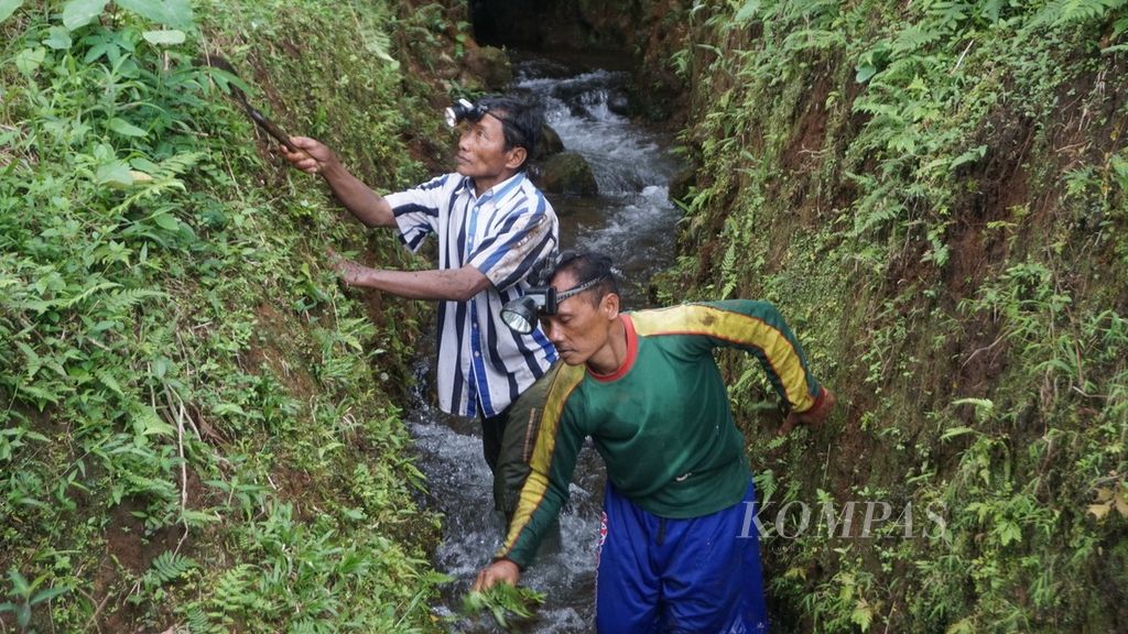 Kusnanto (kiri) dan Agus Salimin membersihkan terowongan air sepanjang 550 meter di lereng selatan Gunung Slamet, Banyumas, Jawa Tengah, Jumat (28/1/2022).