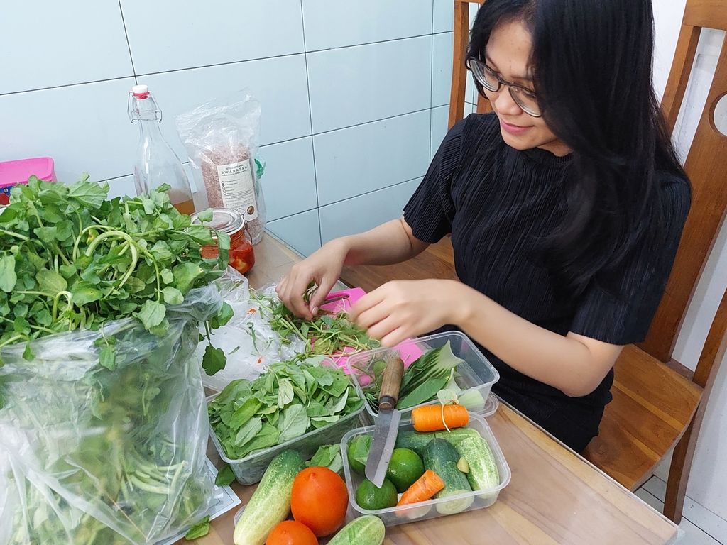 Yola Ayurveda membersihkan bahan-bahan untuk membuat <i>smoothies</i> yang dibeli di Pasar Palmerah, Jakarta Pusat, Sabtu (18/6/2022). Setelah dibersihkan, sayuran dimasukkan ke dalam stoples atau wadah untuk disimpan di kulkas.