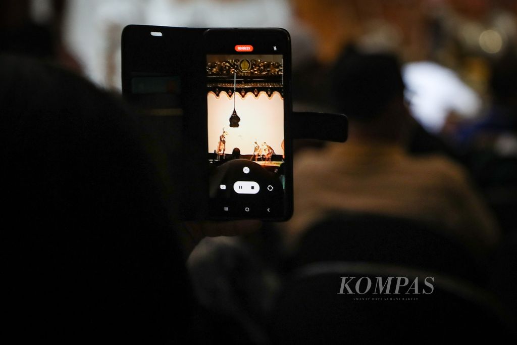 Seorang penonton merekam pergelaran wayang kulit Surakarta dengan dalang Ki Galih Tri Atmojo di Museum Wayang, Kota Tua, Jakarta, Minggu (23/7/2023). 