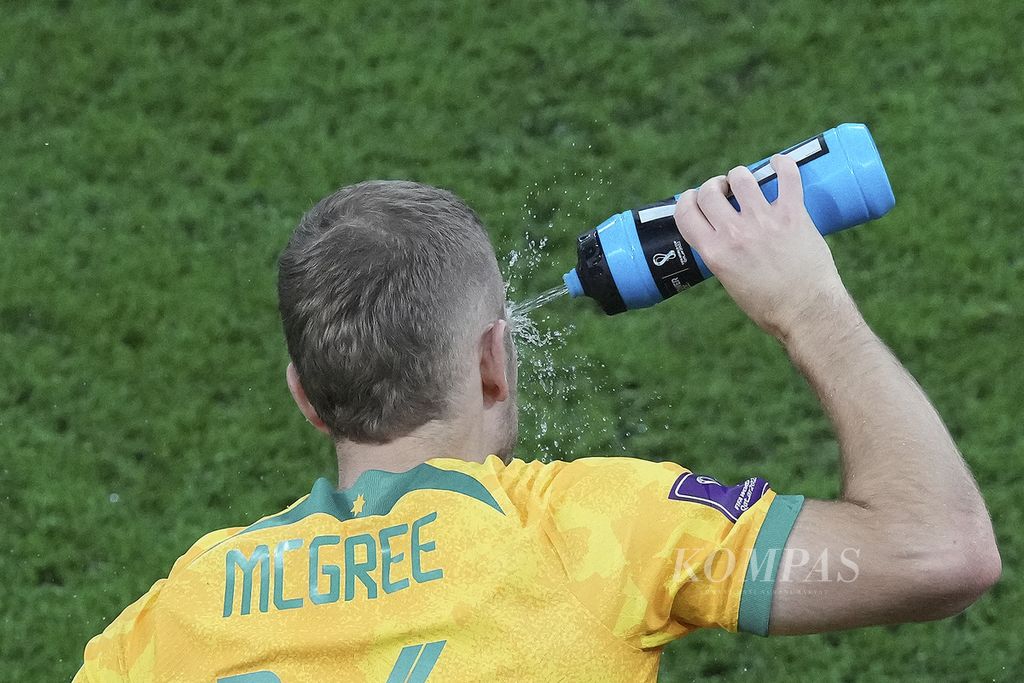Pemain Australia, Riley McGree, menyemprotkan air ke mukanya saat bertanding melawan Argentina di babak 16 besar Piala Dunia 2022 di Stadion Ahmad Bin Ali, Qatar, Minggu (4/12/2022) dini hari WIB.