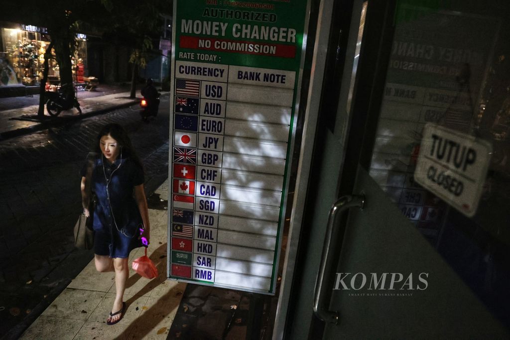 Wisatawan asing melintas di depan tempat penukaran uang di Jalan Pantai Kuta, Badung, Bali, Kamis (10/11/2022). 
