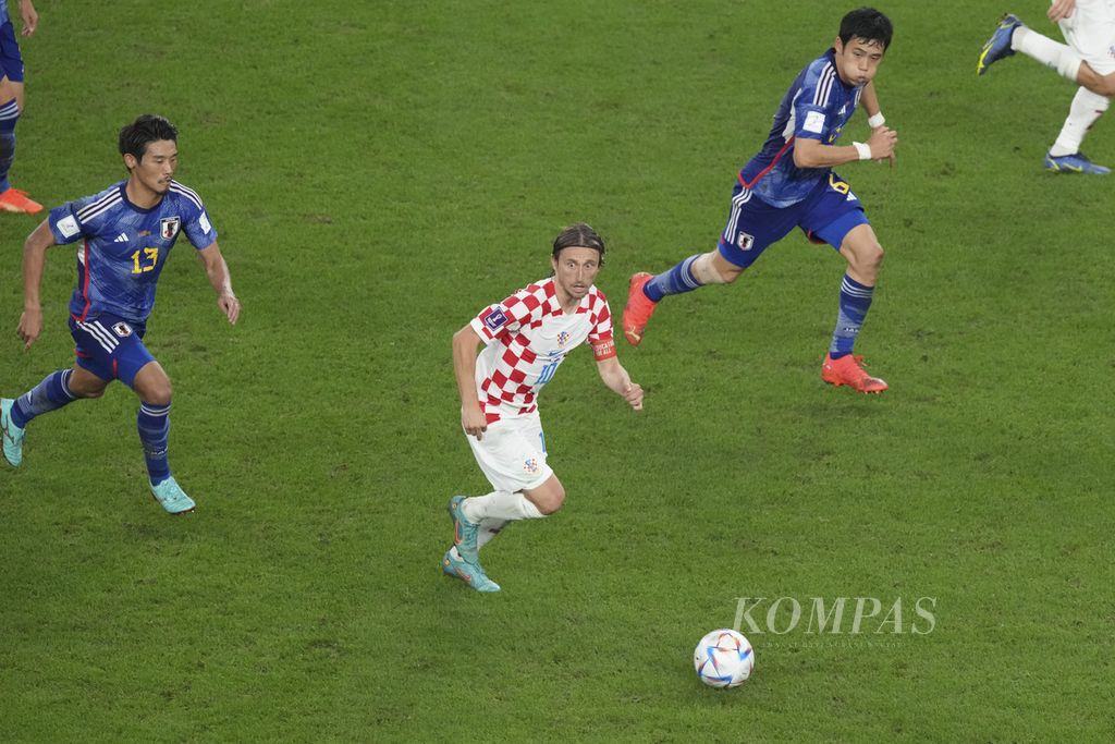 Pemain Kroasia Luka Modric melewati pemain Jepang dalam pertandingan babak 16 besar Piala Dunia 2022 di Stadion Al Janoub, Qatar, Senin (5/12/2022). Kroasia melaju ke babak perempat final setelah mengalahkan Jepang lewat babak adu penalti 4-2 (1-1). 