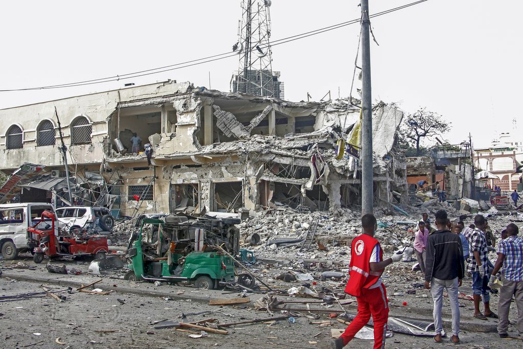 Sejumlah warga memperhatikan bangunan dan kendaraan yang rusak berat di lokasi ledakan bom mobil di Mogadishu, Somalia, Sabtu (29/10/2022).