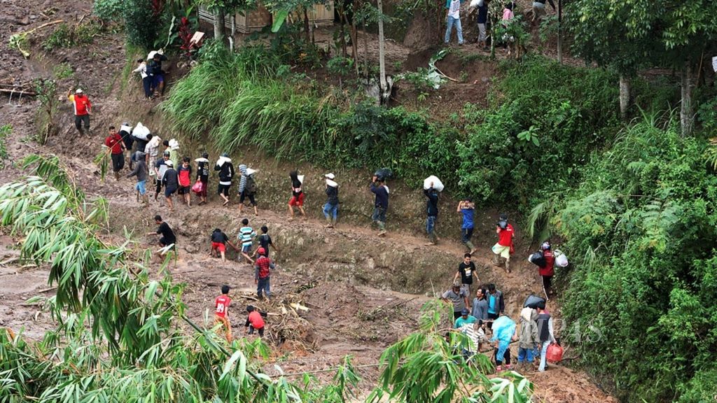 Warga mengangkut bantuan dari posko bencana ke sejumlah desa yang terisolasi karena longsor di Desa Pasir Madang, Kecamatan Sukajaya, Kabupaten Bogor, Minggu (5/1/2020).