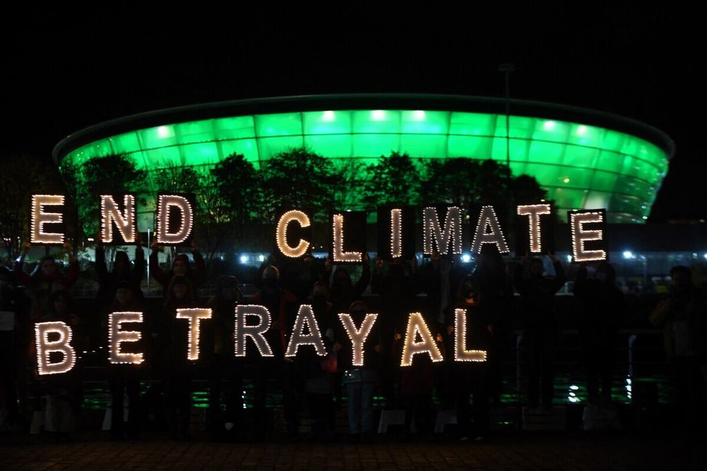 Aktivis memegang papan tulisan bercahaya yang membentuk kalimat Akhiri Pengkhianatan Iklim di Glasgow, Skotlandia, awal November 2021, di tengah Konferensi Iklim Ke-26. 