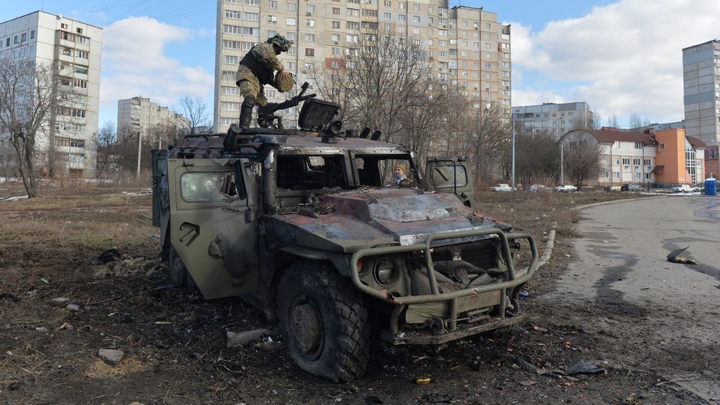 Seorang pejuang Pertahanan Teritorial Ukraina memeriksa kendaraan mobilitas infanteri Rusia GAZ Tigr yang hancur setelah pertempuran di Kharkiv, Ukraina, Sabtu (27/2/2022). 