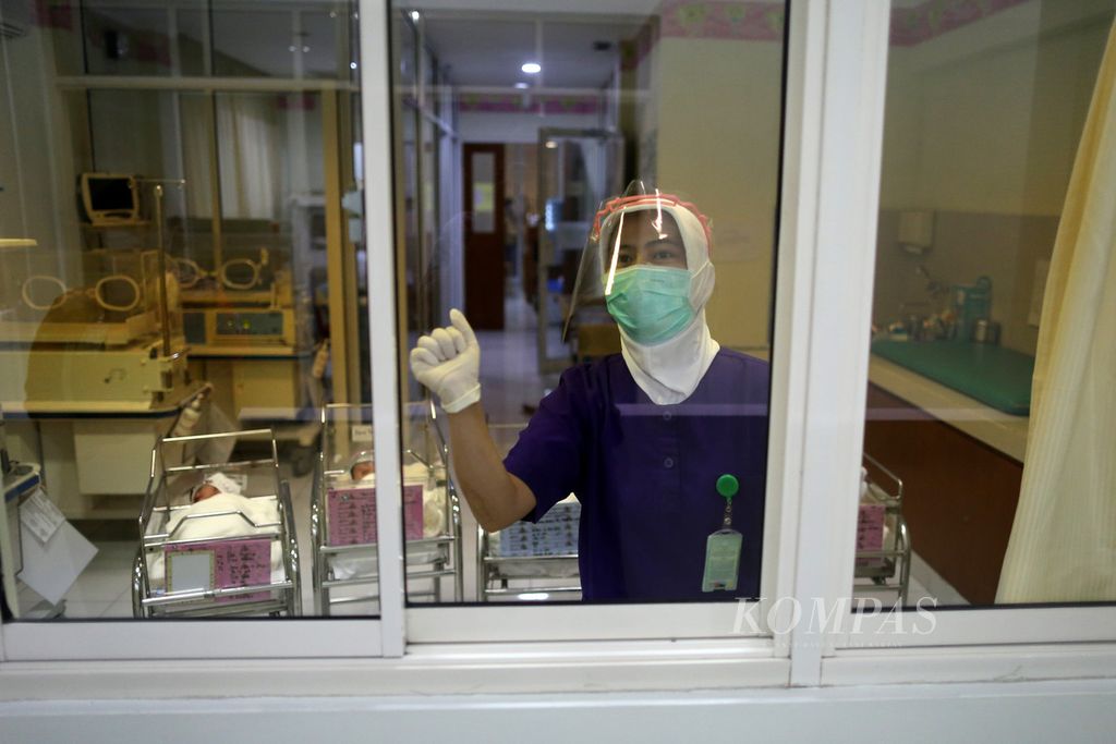 Perawat menjaga bayi yang baru lahir di ruang bayi Rumah Sakit Ibu dan Anak Tambak, Jakarta, Senin (20/4/2020). Baik bayi maupun perawat mengenakan pelindung wajah (<i>face shield</i>). Kebijakan internal pemasangan pelindung wajah pada bayi yang baru lahir ini dilakukan untuk meminimalkan bayi terpapar virus korona baru melalui <i>droplet</i>.