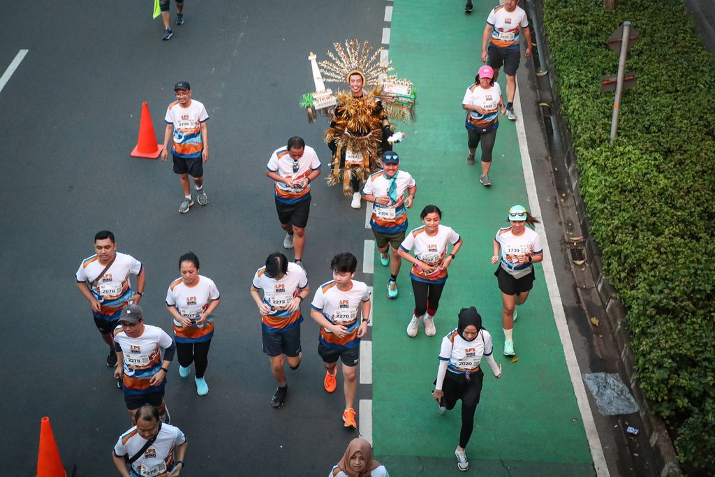 Para peserta "Run The City" melintasi di Jalan Jenderal Sudirman, Jakarta, Sabtu (1/7/2023). 