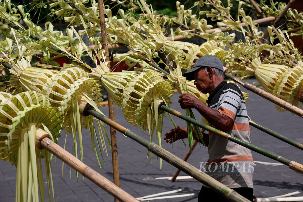 Pekerja menyelesaikan pembuatan hiasan janur yang akan dipasang sepanjang jalan menuju Pura Mangkunegaran di Kota Surakarta, Jawa Tengah, Sabtu (10/12/2022). 
