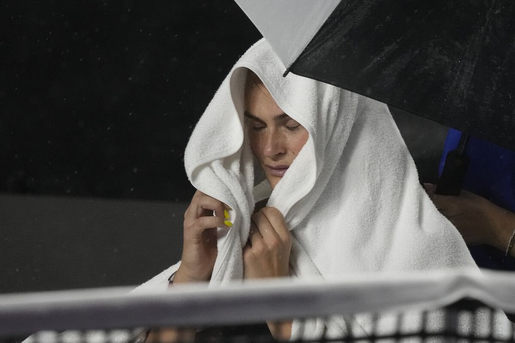 Petenis Belarus, Aryna Sabalenka, menutup kepalanya saat hujan di tengah pertandingan babak grup turnamen Final WTA melawan petenis Kazakhstan, Elena Rybakina, di Cancun, Meksiko, Jumat (3/11/2023) siang WIB. Pertandingan tersebut ditunda akibat faktor cuaca.