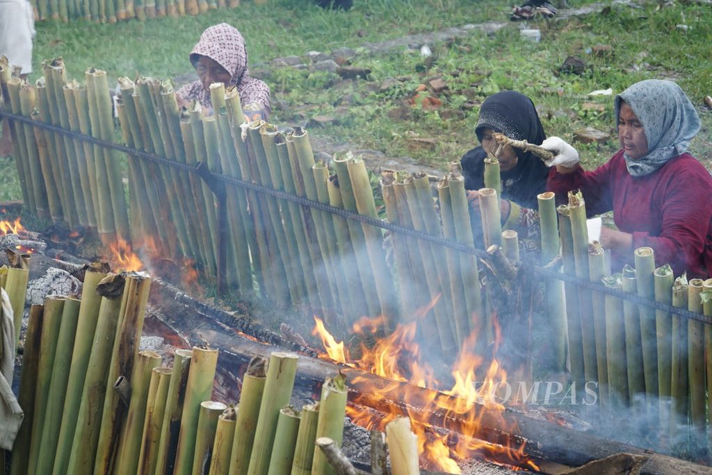 Warga memperbaiki posisi tabung lamang (lemang) agar matang merata dalam acara "Malamang Sakampuang" di Kelurahan Aie Pacah, Kecamatan Koto Tangah, Kota Padang, Sumatera Barat, Sabtu (31/12/2022). 