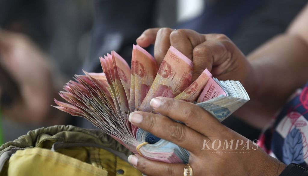 Penjual jasa penukaran uang menghitung uang pecahan Rp 100.000 dan Rp 50.000 di kawasan Jalan Pintu Besar Selatan, Jakarta Barat, Sabtu (8/5/2021). 
