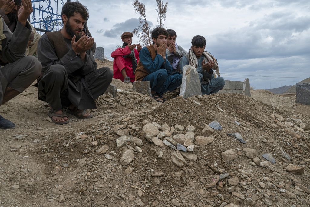 Sejumlah laki-laki kerabat korban ledakan bom bunuh diri di Masjid Siddiquiya, Kabul, Afghanistan, berdoa di depan makam salah satu korban, Kamis (18/8/2022). Sedikitnya 24 juta warga Afghanistan butuh bantuan kemanusiaan. Selain itu, 3 juta anak Afghanistan kekurangan nutrisi.