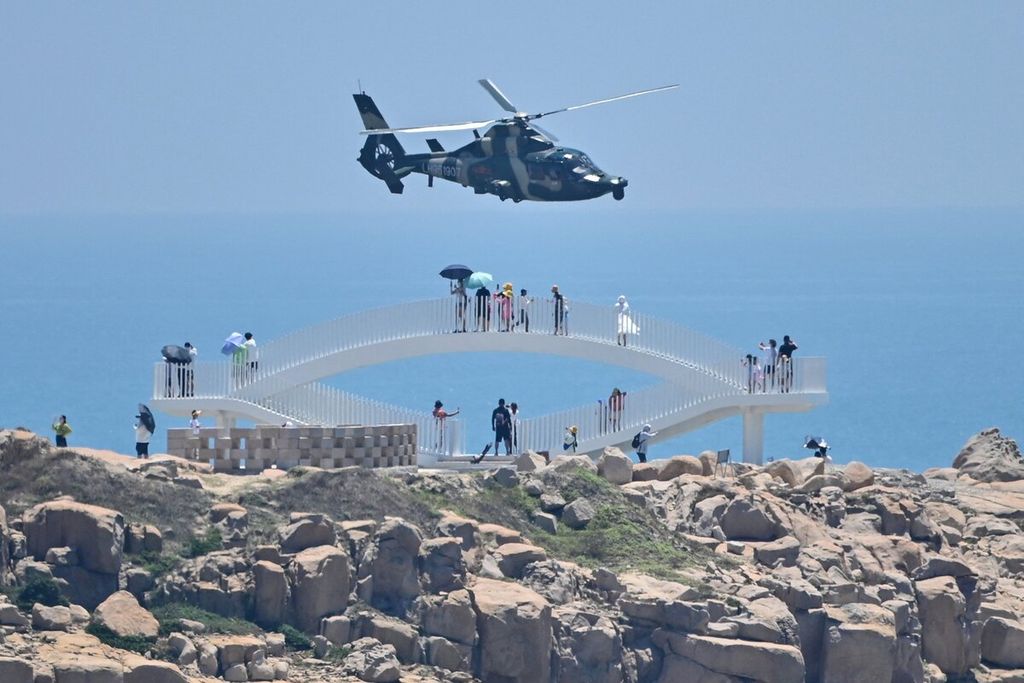 Sejumlah wisatawan melihat helikopter militer China saat terbang melewati Pulau Pingtan, salah satu titik terdekat antara China daratan dan Taiwan, di Provinsi Fujian, China, Kamis (4/8/2022). 