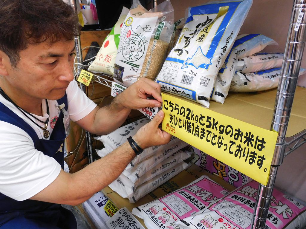 Foto pada 25 Juli 2024 ini memperlihatkan pekerja supermarket memasang tanda yang memberi tahu pelanggan agar hanya membeli satu kantong beras per orang di Tokyo, Jepang. 