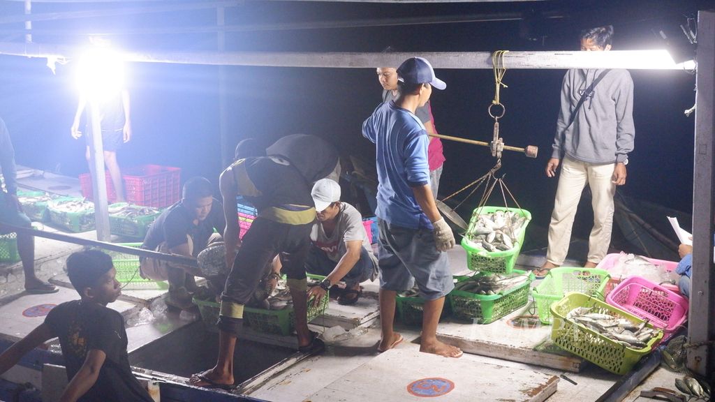 Nelayan dan pedagang menimbang ikan saat bongkar muat ikan laut di Pelabuhan Perikanan Banjarmasin, Kalimantan Selatan, Jumat (24/6/2022) malam. 