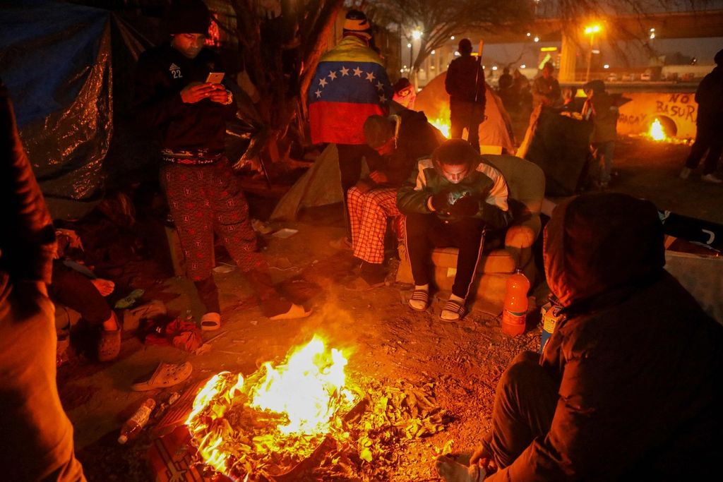 Para imigran dari Venezuela membuat api unggun untuk menghangatkan diri pada malam Natal 24 Desember 2022. Mereka terkatung-katung di Ciudad Juarez, Meksiko, karena tidak bisa masuk ke Amerika Serikat.