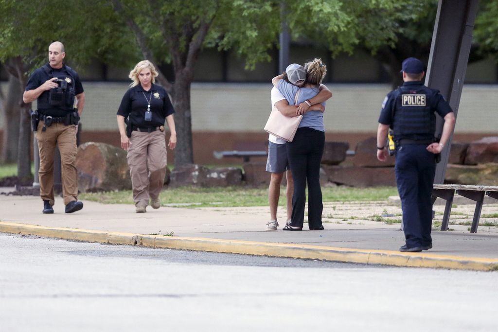 Dua orang berpelukan di luar Memorial High School, tempat orang-orang dievakuasi dari lokasi penembakan di Tulsa, Oklahoma, AS, Rabu (1/6/2022) waktu setempat. 
