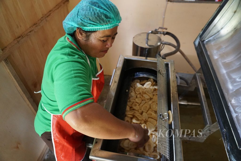 Ni Luh Sariwati (47) memasukkan buah salak ke dalam tabung mesin penggoreng hampa udara (<i>vacuum frying</i>) untuk mengolahnya menjadi keripik di Desa Werdhi Agung Selatan, Selasa (19/7/2022).
