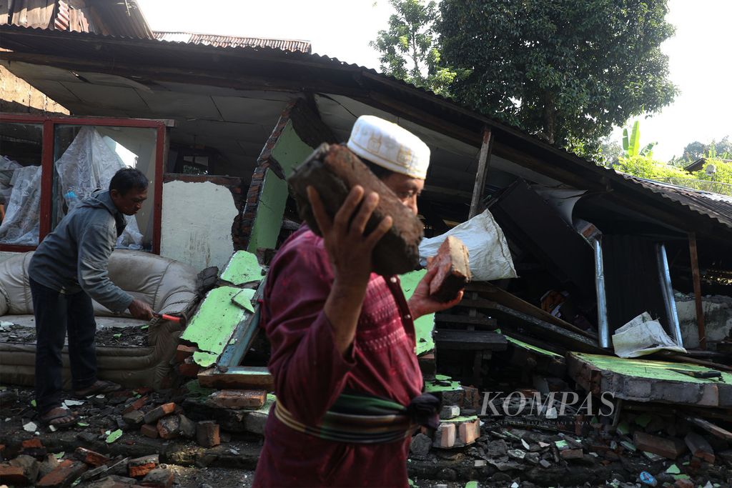 Warga dibantu para sukarelawan menyingkirkan puing-puing bangunan yang roboh karena gempa di Nagari Kajai, Kecamatan Talamau, Kabupaten Pasaman Barat, Sumatera Barat, Senin (28/2/2022).