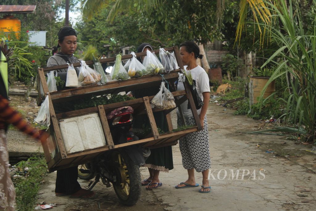 Resi, warga Desa Kalumpang, Kabupaten Kapuas, Kalimantan Tengah, membeli sayuran pada paman sayur di desanya, Senin (18/7/2022).