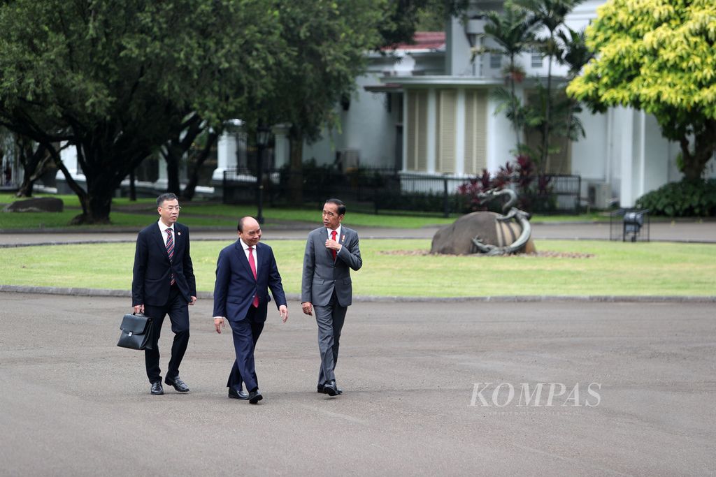 Presiden Joko Widodo bersama Presiden Vietnam Nguyen Xuan Phuc (tengah) berjalan menuju veranda seusai menanam pohon di Istana Kepresidenan, Bogor, Jawa Barat, Kamis (22/12/2022).  