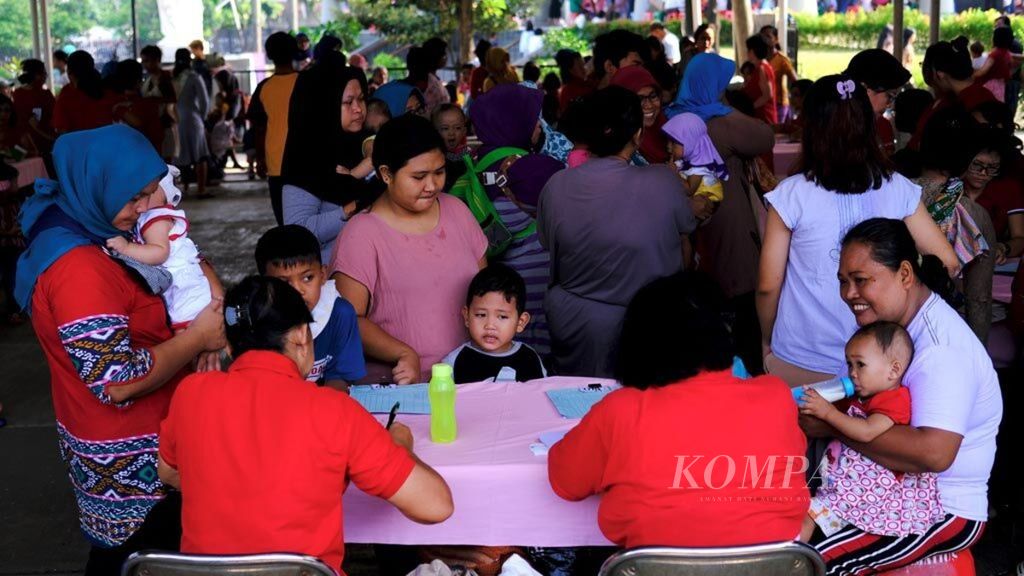 Petugas melayani warga yang datang untuk memantau kesehatan anaknya di Posyandu Matius 25, Pondok Karya, Tangerang Selatan, Banten, Minggu (16/6/2019).