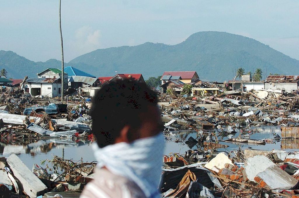 Ilustrasi bencana. Warga melintasi permukiman yang hancur tersapu gempa dan gelombang tsunami di Lampare Kota, Banda Aceh, Provinsi Nanggroe Aceh Darussalam, Selasa (28/12/2004).