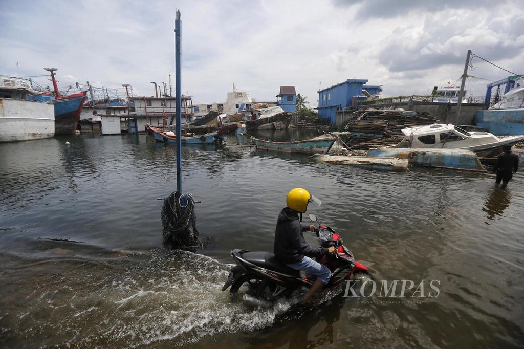 Pengendara bermotor berusaha melalui banjir rob yang menggenangi beberapa titik di kawasan Pelabuhan Perikanan Samudera Nizam Zachman, Jakarta Utara, Minggu (8/1/2023). 