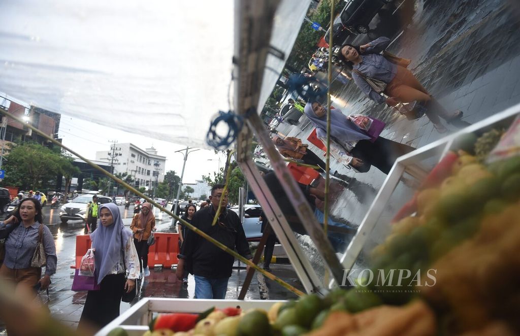 Refleksi pekerja pulang dari kantor di Jalan Embong Malang, Surabaya, Senin (26/2/2024). Saat ini sebagian besar kelas menengah usia 17-40 tahun kerepotan mengatur pengeluaran. Pengeluaran terbesar kelas menengah Indonesia untuk membeli kendaraan bermotor serta cicilan perumahan. 