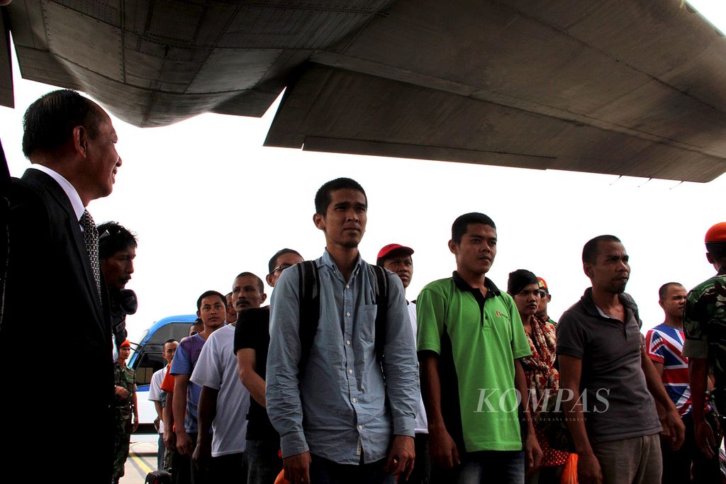 Indonesian Migrant Workers (TKI) who work in Malaysia gather before entering the Indonesian Air Force's Hercules plane that picked them up at the Subang Air Base, Malaysia, to be sent home, Tuesday (12/23/2014).