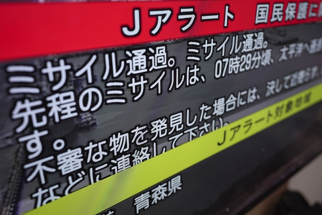 Siaran televisi menunjukkan J-Alert atau Sistem Peringatan Dini Nasional untuk warga Jepang pada 4 Oktober 2022 di Tokyo. Peringatan dikeluarkan menyusul peluncuran rudal balistik Korea Utara yang melintasi wilayah Jepang. Tulisan itu berbunyi: ”Rudal melintas. Rudal melintas”. 