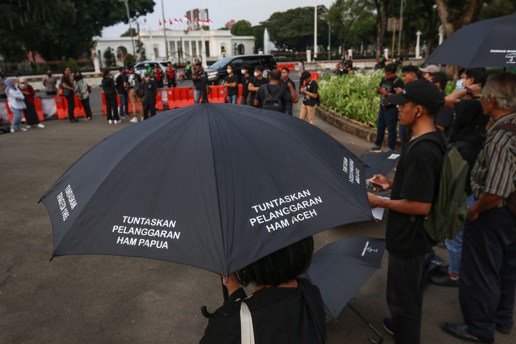 Seorang aktivis membawa payung bertuliskan tuntutan penuntasan pelanggaran HAM dalam Aksi Kamisan ke-759 di depan Istana Merdeka, Jakarta, Kamis (12/1/2023). Pada Aksi Kamisan ke-759, Jaringan Solidaritas Korban untuk Keadilan (JSKK) menyoroti pengakuan dan penyesalan Presiden Joko Widodo atas terjadinya pelanggaran hak asasi manusia berat di 12 peristiwa masa lalu. JSKK menganggap pengakuan dan penyesalan tersebut tidak ada artinya jika tidak diikuti dengan langkah konkret pertanggungjawaban hukum.