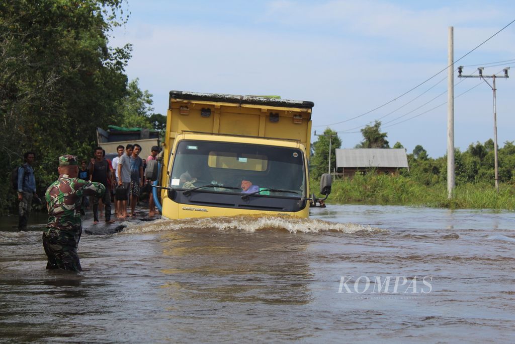 Babinsa Dusun Selatan mengatur antrean kendaraan yang memaksa melewati titik terparah banjir di Trans-Kalimantan, Kabupaten Barito Selatan, Kalteng, pada Kamis (25/1/2024). Akses itu masih terputus lantaran banjir yang melanda.